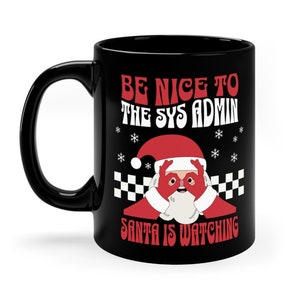 Könnte beinhalten: Schwarze Keramik-Tasse mit weißem Henkel und Santa Claus-Design. Die Tasse trägt den Text "BE NICE TO THE SYS ADMIN SANTA IS WATCHING" in Rot und Weiß, mit Schneeflocken und einem Schachbrettmuster.