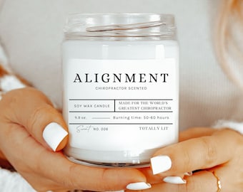 Peut inclure: Une bougie en cire de soja blanche avec une étiquette noire qui indique "ALIGNMENT CHIROPRACTOR SCENTED" et "MADE FOR THE WORLD'S GREATEST CHIROPRACTOR". La bougie est dans un pot en verre transparent avec un couvercle blanc.