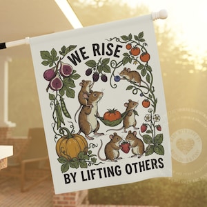 May include: A rectangular garden flag featuring an illustration of five brown mice harvesting fruits and vegetables. The text WE RISE BY LIFTING OTHERS is printed in black. The mice are surrounded by vines with figs, tomatoes, and berries.