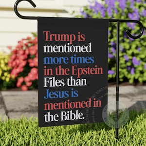 May include: A rectangular black garden flag hanging on a black metal stand. The flag features white, red, and blue text that reads: Trump is mentioned more times in the Epstein Files than Jesus is mentioned in the Bible.