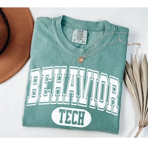 Op de afbeelding: Een tealblauw t-shirt met de tekst "BEHAVIOR TECH" in wit. Het shirt is gemaakt van een zacht, comfortabel materiaal en heeft een vintage look.