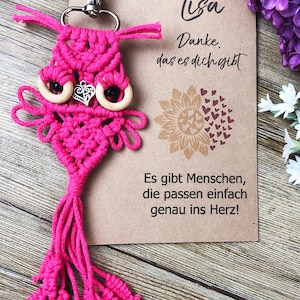 May include: Pink macrame owl keyring with wooden eyes and a silver heart charm. The keyring is attached to a card with the text "Lisa Danke. das es dich gibt Es gibt Menschen, die passen einfach genau ins Herz!"