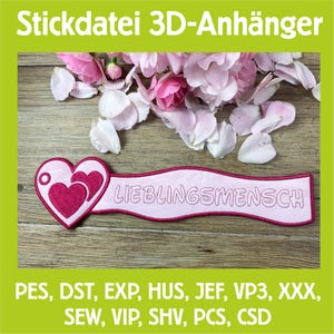 Könnte beinhalten: Ein rosa-weißes, gesticktes herzförmiges Applikationsmotiv mit dem deutschen Wort "LIEBLINGSMENSCH" auf einem Banner. Das Bild enthält den Text "Stickdatei 3D-Anhänger" und verschiedene Dateiformat-Abkürzungen. Rosa Blütenblätter sind im Hintergrund verstreut.