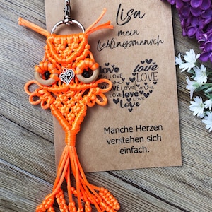 May include: Orange macrame owl keyring with wooden eyes and a silver heart charm. The keyring is attached to a brown card with the text "Lisa mein Lieblingsmensch" and "Manche Herzen verstehen sich einfach."