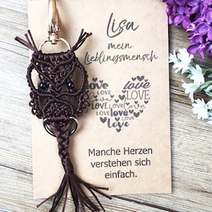 May include: Brown macrame owl keychain with black eyes and a heart-shaped design with the words "Love" and "Lisa, mein Lieblingsmensch" on a brown card with the text "Manche Herzen verstehen sich einfach."