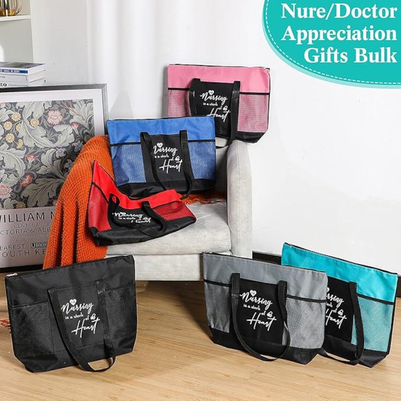 May include: Six tote bags with black handles and mesh pockets. The bags are in various colors, including pink, blue, red, and gray. Each bag has a white heart and the text "Nursing is a work of the heart" printed on the front.