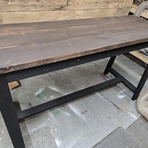 May include: A dark brown wooden table top with a black painted metal base. The table has a simple design with a single shelf.