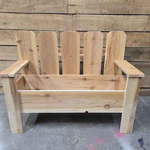 May include: A wooden bench with a planter box built in. The bench has a picket fence style back and is made of natural wood.