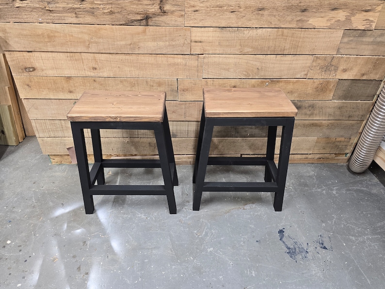 Puede incluir: Dos taburetes de madera con marcos de metal negro. Los taburetes tienen un acabado de madera natural y son de un dise&ntilde;o simple y moderno.
