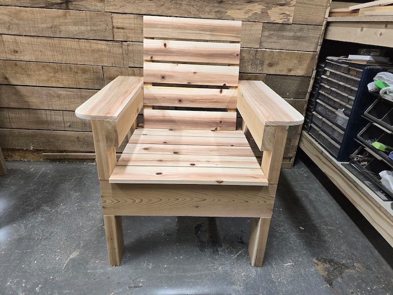May include: A wooden chair with a slatted back and armrests. The chair is made of unfinished wood and has a simple design.