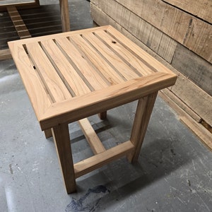 May include: A small, wooden side table with a slatted top and a simple, rectangular frame. The table is made of light-colored wood and has a natural finish.