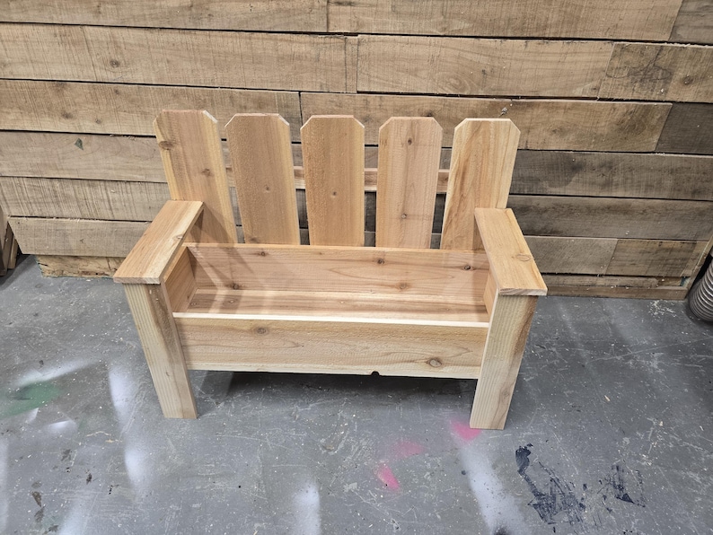May include: A wooden bench with a planter box built in. The bench is made of natural wood and has a simple design. The planter box is empty and ready for plants.