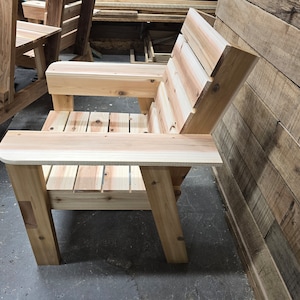 May include: A wooden chair with a slatted back and armrests. The chair is made of natural wood and has a rustic look.