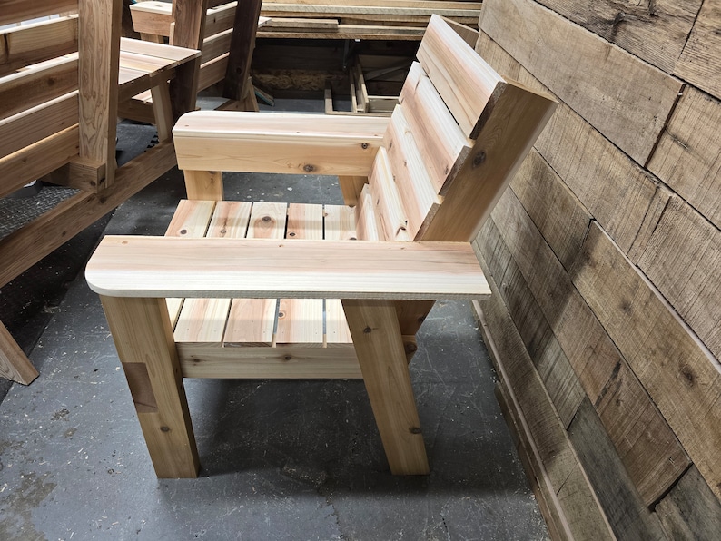 May include: A wooden chair with a slatted back and armrests. The chair is made of natural wood and has a rustic look.