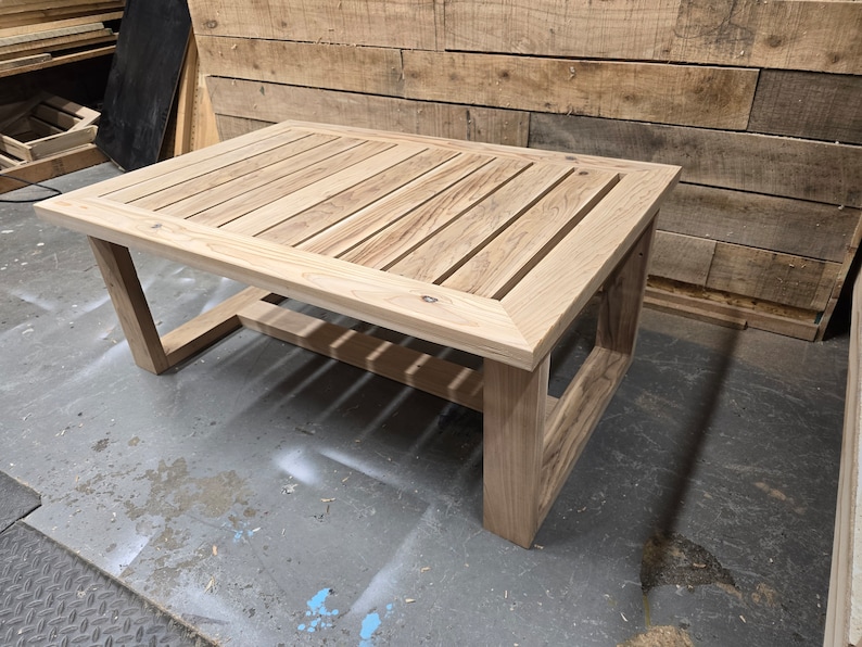 May include: A wooden coffee table with a slatted top and a simple, rectangular frame. The table is made of light-colored wood and has a natural finish.