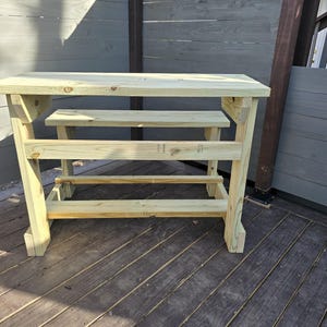 May include: A wooden table with a bench attached. The table and bench are made of unfinished wood and have a rustic look.