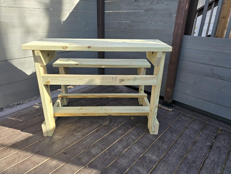 May include: A wooden table with a bench attached. The table and bench are made of unfinished wood and have a rustic look.