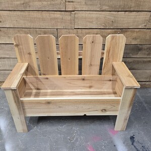 May include: A wooden bench with a picket fence design on the back. The bench has a planter box built into the seat.