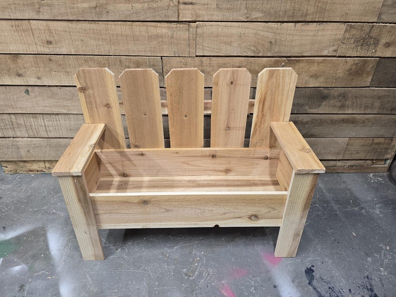 May include: A wooden bench with a picket fence design on the back. The bench has a planter box built into the seat.