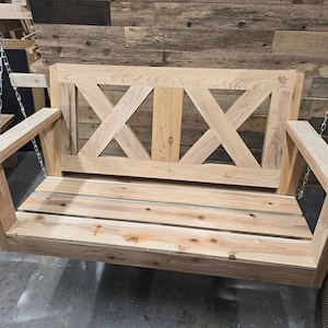 May include: A wooden swing bench with a slatted seat and a decorative X-shaped back. The swing is hanging from two chains.