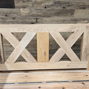 May include: A wooden swing with a slatted seat and a decorative X-shaped back. The swing is made of natural wood and has a rustic look.