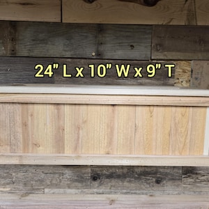 Peut inclure: Une boîte rectangulaire en bois avec un dessus et des côtés de couleur claire. La boîte mesure 61 cm de long, 25 cm de large et 23 cm de haut. La boîte est en bois clair et a une finition naturelle.