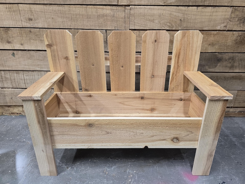 May include: A wooden bench with a planter box built in. The bench is made of natural wood and has a picket fence style back.