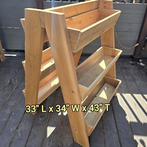 May include: A wooden three-tiered planter stand with three rectangular planters. The stand is 84 cm L x 86 cm W x 109 cm T.