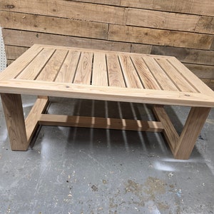May include: A rectangular wooden coffee table with a slatted top and a simple, modern frame. The table is made of light-colored wood and has a natural finish.