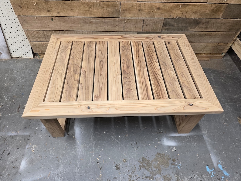 May include: A rectangular wooden coffee table with a slatted top and a natural wood finish. The table has a simple, modern design and is perfect for any living room or outdoor space.