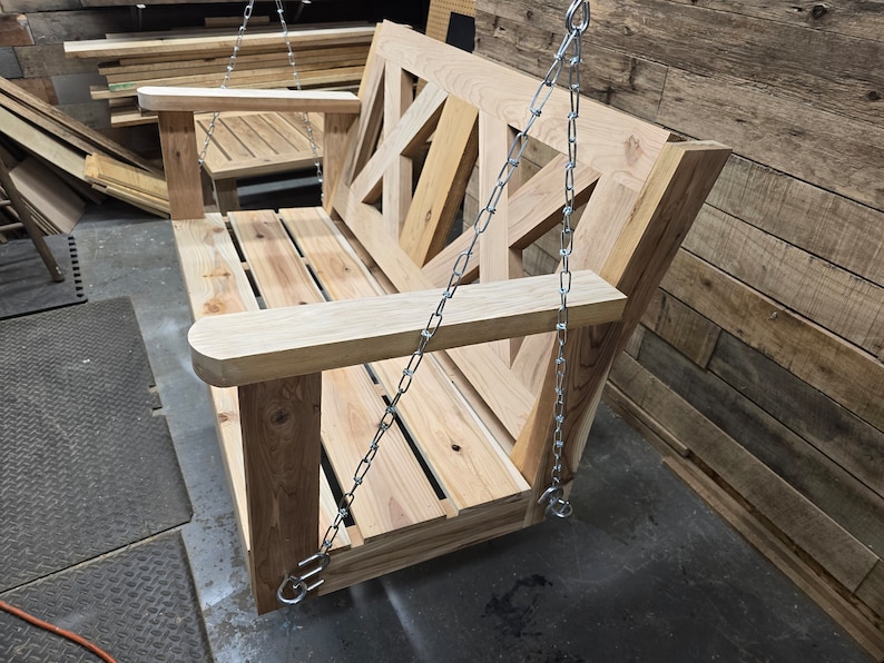 May include: A wooden swing bench with a geometric design on the back. The swing is suspended by two silver chains.