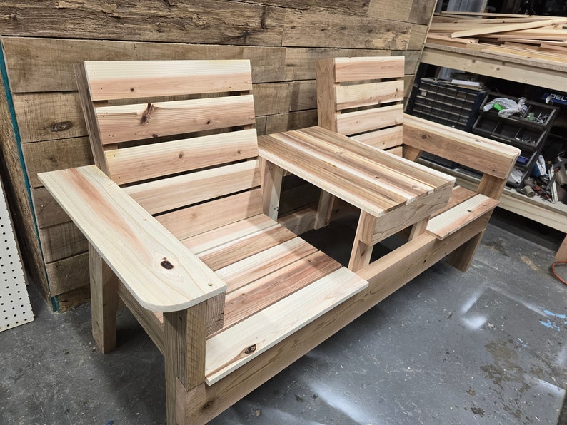 Pu&ograve; includere: Una panca in legno con un tavolo integrato al centro. La panca &egrave; realizzata con assi di legno naturale e ha un aspetto rustico.