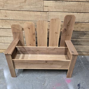 Pode incluir: Um banco de madeira com uma caixa de planta integrada no assento. O banco é feito de madeira natural com um acabamento rústico. A caixa de planta está vazia e pronta para plantas.