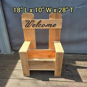 Może przedstawiać: Drewniana donica w kształcie krzesła z napisem "Welcome" w czarnym skrypcie. Donica ma 45,7 cm długości, 25,4 cm szerokości i 71,1 cm wysokości. Ma naturalne drewniane wykończenie i jest przeznaczona do przechowywania roślin.