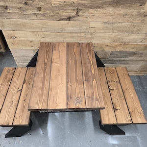 May include: A wooden picnic table with two benches. The table and benches are made of brown stained wood and have a black metal frame.