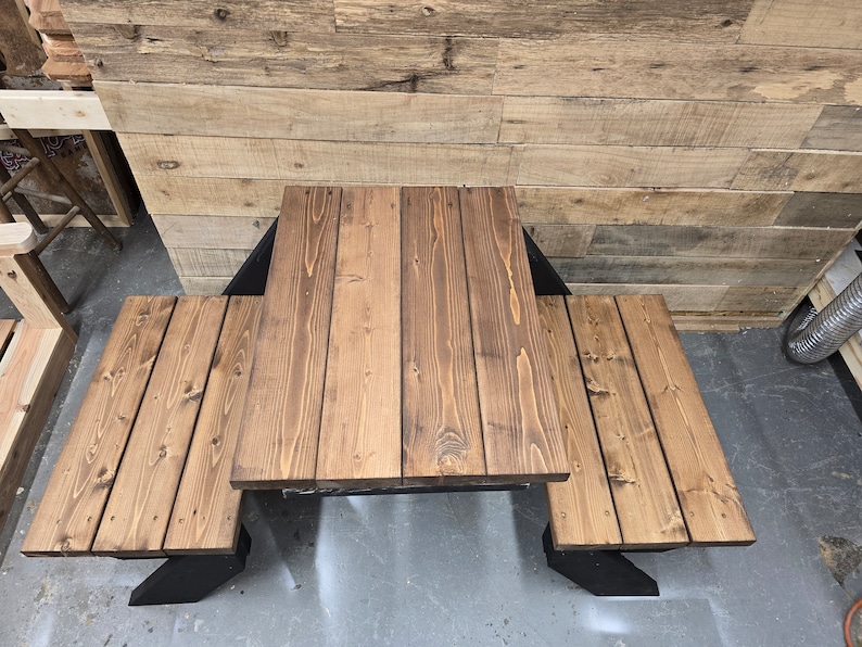 May include: A wooden picnic table with two benches. The table and benches are made of brown stained wood and have a black metal frame.