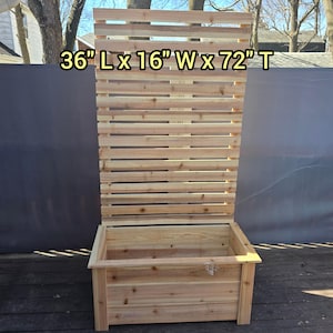 May include: A wooden planter box with a slatted back, measuring 36" long, 16" wide, and 72" tall. The natural wood has visible grain and is constructed with horizontal slats for the back. The planter box is designed for outdoor use.