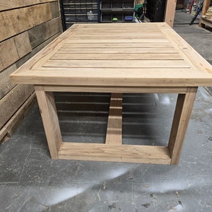 May include: A light wood table with a slatted top and a simple, rectangular frame. The table is made of unfinished wood and has a natural, rustic look.