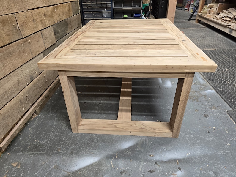 May include: A light wood table with a slatted top and a simple, rectangular frame. The table is made of unfinished wood and has a natural, rustic look.