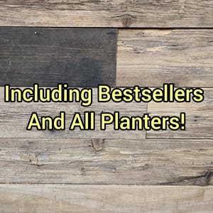 Może przedstawiać: Drewniane tło z ż&oacute;łtym napisem "Including Bestsellers And All Planters!". Drewno ma rustykalny, zwietrzały wygląd z r&oacute;żnymi odcieniami brązu i szarości.