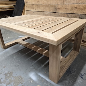 May include: A wooden coffee table with a slatted top and a simple, rectangular frame. The table is made of light-colored wood and has a natural finish.