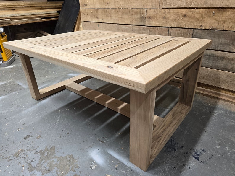 May include: A wooden coffee table with a slatted top and a simple, rectangular frame. The table is made of light-colored wood and has a natural finish.