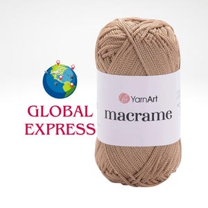 Peut inclure: Pelote de fil YarnArt macramé de couleur beige. L'étiquette affiche le logo YarnArt et le mot "macramé". L'image comprend également les mots "GLOBAL EXPRESS" avec un globe et un avion.