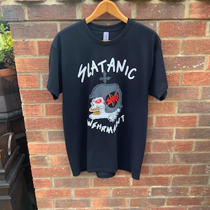 May include: Black t-shirt with a white graphic of a skull wearing a helmet with the word "SLATANC" above it and "WEHRMACHT" below it.