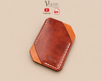May include: A brown leather card holder with a lighter tan leather accent piece, featuring white contrast stitching along the edges and the embossed text VAKSIN. Above the card holder, the text VAKSIN appears with a YouTube and PDF icon.