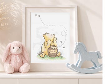 May include: A framed wall art print featuring a yellow bear sitting on green grass next to a brown honey pot labeled HUNNY. The illustration includes a dotted line path of flying bees. The print is displayed in a white frame with a light border.