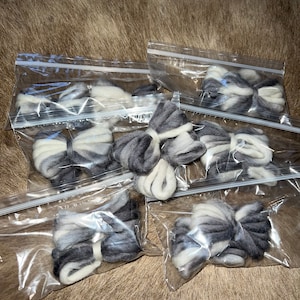 May include: Six small bags of white and gray wool roving, each tied in a bow shape.