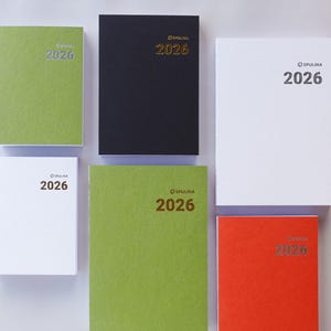 Könnte beinhalten: Sechs Spulina 2026 Notizbücher in verschiedenen Farben: Grün, Schwarz, Weiß und Orange. Die Notizbücher haben einen strukturierten Einband und das Jahr 2026 ist auf der Vorderseite aufgedruckt. Das Spulina-Logo ist ebenfalls sichtbar.
