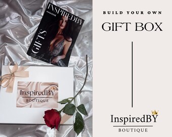 May include: A white gift box with a red rose and a small card that says "InspiredBY Boutique". The box is on a white satin fabric. The image also includes a magazine cover with the text "InspiredBY Magazine" and the word "Gifts". The text "BUILD YOUR OWN GIFT BOX" is in the upper right corner of the image. The text "InspiredBY BOUTIQUE" is in the lower right corner of the image.
