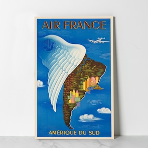 Peut inclure: Une affiche de voyage vintage pour Air France représentant une aile blanche stylisée sur une carte de l'Amérique du Sud, avec le texte "AIR FRANCE" et "AMERIQUE DU SUD".